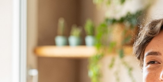 Junge Frau putzt lachend die Zähne im Spiegel