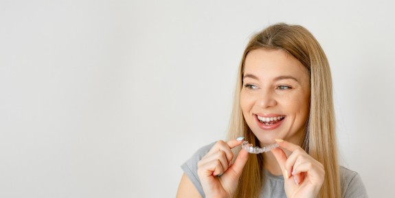 Junge Frau hält lachend eine Zahnschiene