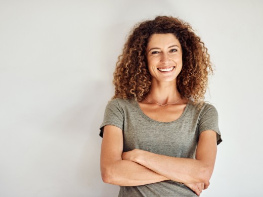 Frau mit verschränkten Armen lächelt selbstbewusst