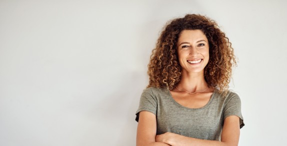 Frau mit verschränkten Armen lächelt selbstbewusst