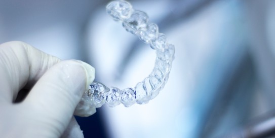 Person hält Zahnschiene mit Gummihandschuhen