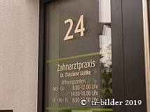 Glastür mit der Hausnummer 24 und Beschriftung der Zahnarztpraxis Dr. Christiane Lüdtke inklusive Öffnungszeiten.
